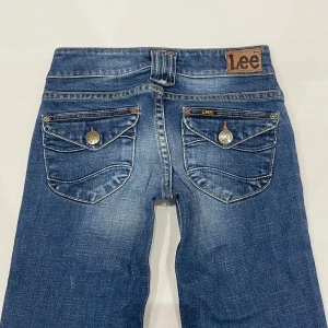 Lågmidjade bootcut jeans från Lee🤩 - Midja 33 cm rakt över, gren 17 cm och innerben 78 cm💕får inte dessa över rumpan men gjort mitt bästa för att visa hur de sitter på