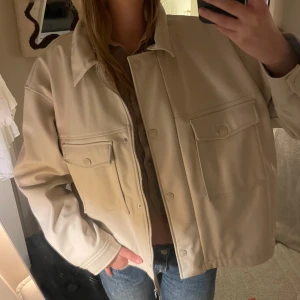 Skinnjacka - Beige skinnjacka som är oanvänd med lappen kvar. Har både dragkedja och knappar. 