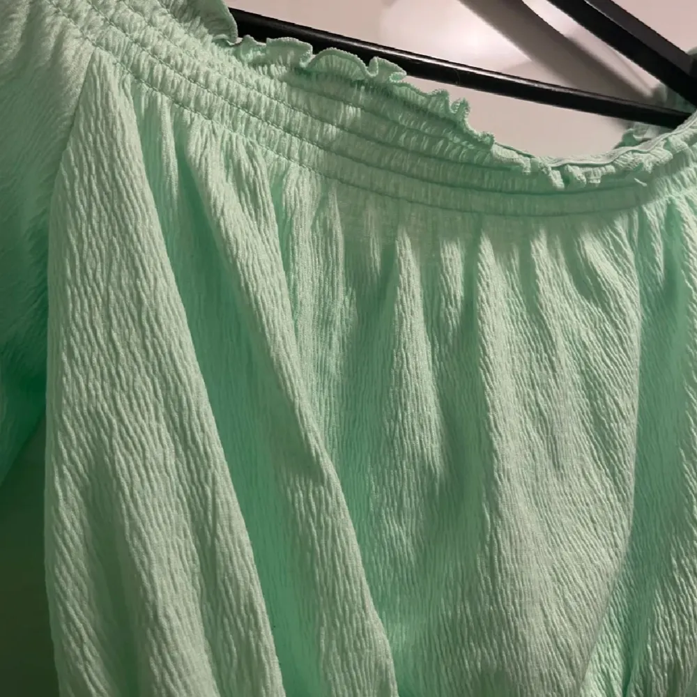 Säljer en superfin mintgrön offshoulder topp från Divided. Den är croppad och har långa ärmar med elastiska detaljer vid axlar och midja för en perfekt passform. Perfekt för sommarens fester eller en dag på stan! Använd en gång!. Tröjor & Koftor.