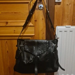 Svart väska - Ny svart väska i skinliknande (tror det är någon slags imitation) har några enstaka märken, men inget som syns tydligt! Väldigt mycket plats i den. Vissa läder "snören" står åt olika håll men de är enkla att forma om! (Jag gör det bästa möjliga själv