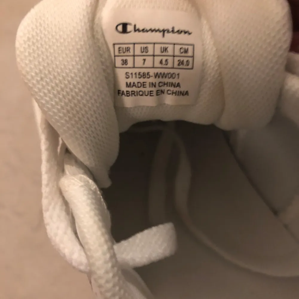 Säljer ett par snygga vita sneakers från Champion i storlek 38. Skorna är i nyskick och har en klassisk design med snörning och Champion-loggan på sidan. Perfekta för både vardag och träning!. Skor.