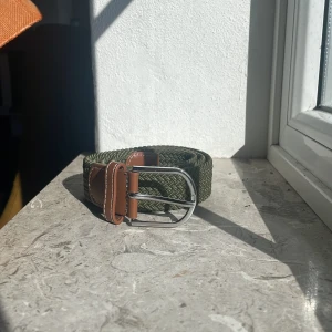 Grönt flätat bälte med bruna detaljer - Säljer ett grönt flätat bälte som du kan ha på dig till vad som. 