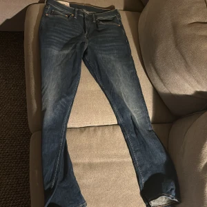 Blå slim fit jeans från H&M - Snygga blå slim fit jeans från H&M. De har en klassisk femficksdesign och är perfekta för en stilren look. Tillverkade i ett bekvämt tyg som ger en skön passform.