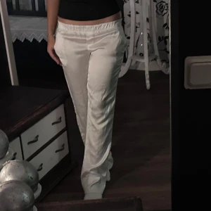 vita byxor  - Snygga vita byxor med resårmidja som ger en bekväm passform. Byxorna har en loose stil och är perfekta för en avslappnad look. De är tillverkade i ett lätt och luftigt material som ger en skön känsla. Midjemåttet är 32 cm, innerbenslängden är 80 cm.