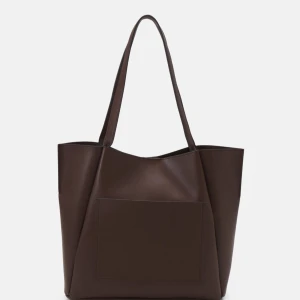 Brun axelväska  - Snygg brun axelväska i syntetmaterial med en stilren design. Väskan har långa axelremmar och en praktisk ytterficka. Perfekt för att bära med sig allt man behöver under dagen.