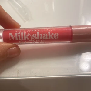 Rosa läppglans från Makeup Mekka - Säljer ett rosa Milkshake Gloss från Makeup Mekka. Läppglanset har en härlig glansig finish och kommer i en smidig tub som är lätt att ta med sig. Perfekt för att ge läpparna en fräsch och glansig look.