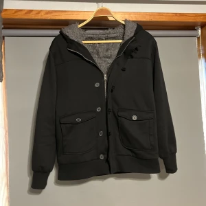 Cardigan jacka med päls - Säljer en svart jacka med mjuk päls innuti . Jackan har dragkedja och knappar framtill samt två stora fickor med knappar. Perfekt för kyliga dagar!