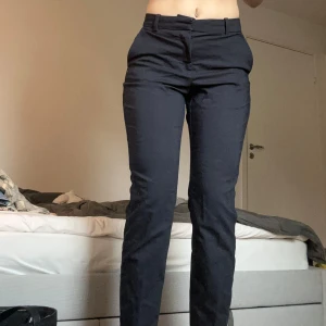 Svarta kostymbyxor från H&M - Snygga svarta kostymbyxor från H&M i storlek 38. De har en klassisk design med knappar och dragkedja framtill. Perfekta för en stilren look. Säljer då de inte är min stil, de har inte använts utan bara legat i garderoben.
