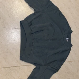 Mörkgrön sweatshirt  - Tröjan har en klassisk design med rund hals och långa ärmar. Perfekt för en avslappnad look.