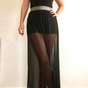 Svart långkjol från H&M Divided - Långkjol i mesh med kort underkjol och silverdetalj i midjan.  Har använts sparsamt, ihop med linnet som också ligger ute på min sida, så det blivit som en klänning.  (Finns på fler säljsidor)