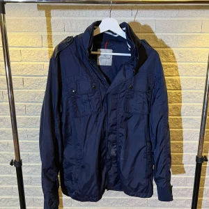 Moncler field jacket - Riktigt snygg Moncler fieldjacket i storlek 3, motsvarar ca M/L. Bra skick utom en fläck på jackan, går troligen bort i tvättten. Hör av dig vid minsta fundering,20
