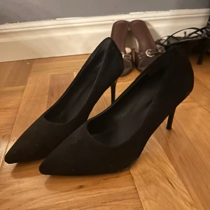 Svarta pumps med spetsig tå - Eleganta svarta pumps med spetsig tå och hög klack. Perfekta för en stilren look. Oanvända klackskor