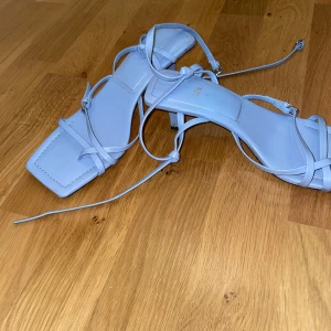 Ljusa blå sandaler från Zara - Snygga ljusblå sandaler från Zara med fyrkantig tå och smala remmar som knyts runt ankeln. Perfekta för en stilren look.