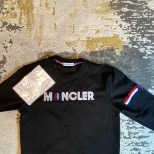 Moncler Tröja - Säljer en snygg svart Moncler tröja.                 Tröjan har stort logga på bröstet samt på vänster ärmen. Perfekt för både vardag och fest! 🖤Skriv för mer info!