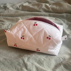 Necessär - Söt vit quiltad necessär med körsbärsmönster. Perfekt för att förvara smink eller hudvård. ❤️🍒Måtten är cirka:     Höjd: 10cm     Längd: 21cm     Bredd: 11cm