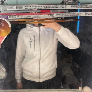 Vit hoodie från sail racing - Säljer en vit hoodie från sail racing med dragkedja och lång ärm. Perfekt för en avslappnad stil. Den har en enkel design med logotyp på bröstet.