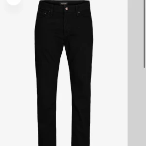 Svarta jeansbyxor från Jack & Jones - Snygga svarta jeansbyxor från Jack & Jones med en klassisk design. De har en normal passform och är perfekta för en stilren look. Byxorna har en dragkedja och knappar framtill. Byxorna kostar 800 i butik men kan gå ner i pris. Dom är 33/30 i storleken