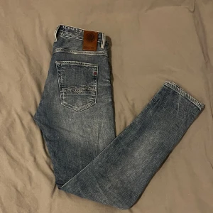 Blå jeans från Replay - Snygga blå jeans från Replay. De har en lätt slitning för en cool look och en läderpatch med logga på baksidan. Perfekta för en avslappnad/trendig stil. Hör av dig vid fundering. 