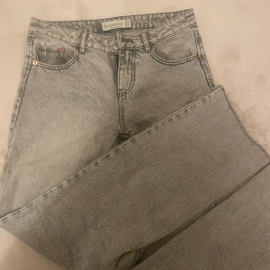 Grå jeans från Stradivarius - Snygga grå jeans från Stradivarius i storlek 36. De har en klassisk femficksdesign och är perfekta för en avslappnad stil. Jeansen har en ljus tvätt och är tillverkade i ett bekvämt material.