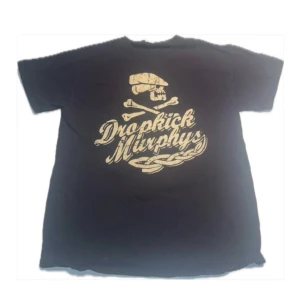 Svart Dropkick Murphys t-shirt - Cool svart t-shirt med Dropkick Murphys-tryck fram och bak. Framsidan har en dödskalle och text, medan baksidan visar ett skepp med bandets namn. 