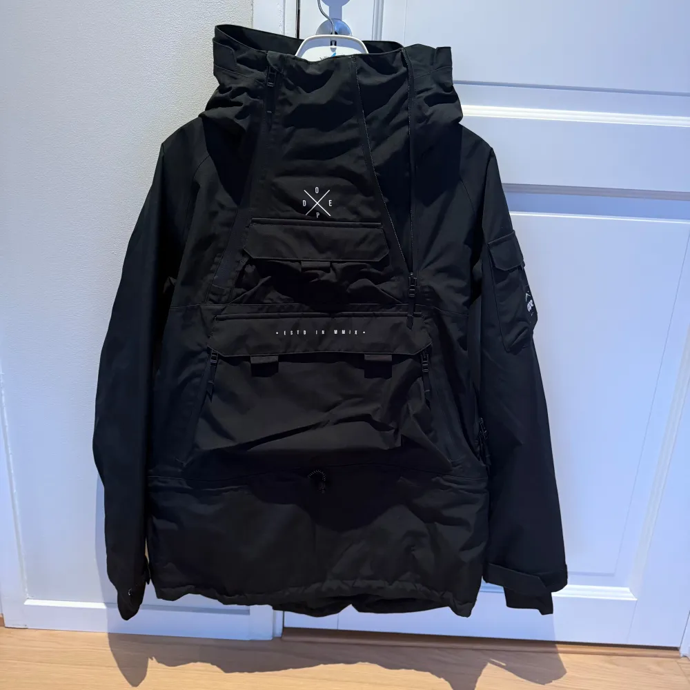 Säljer en svart vindjacka från Dope med en stor ficka framtill och justerbar huva. Jackan har en stilren design med dragkedja och kardborreband vid ärmsluten. Perfekt i skidbacken. https://www.dopesnow.com/se/akin-w-skidjacka-kvinna-black. Takit.