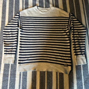 Randig tröja från Denim & Supply Ralph Lauren - Säljer en snygg randig tröja från Denim & Supply Ralph Lauren. Tröjan är i en klassisk marinblå och beige färgkombination med långa ärmar och ribbade muddar. Perfekt för en stilren look. Skicket är bra 8/10 och finns inga defekter. Ifall du vill ha mer information är det bara att höra av dig!!