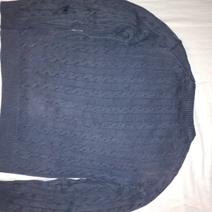 Blå kabelstickad tröja från GANT - Säljer en stilren blå kabelstickad tröja från GANT i premium bomull. Tröjan har en klassisk rund halsringning och långa ärmar med ribbade muddar. Perfekt för en avslappnad och snygg look. Priset kan diskuteras 