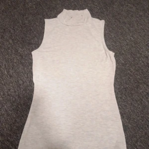 Grå ärmlös polotopp från Gina Tricot - Säljer en stilren grå ärmlös polotopp från Gina Tricot. Perfekt för lager-på-lager eller att bära som den är. Toppen har en mjuk och bekväm passform.