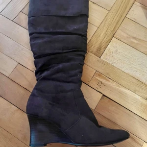 Bruna  stövlar med kilklack - Snygga bruna stövlar i mocka med kilklack och dragkedja på sidan. Perfekta för höst och vinter med en stilren design som passar till många outfits.