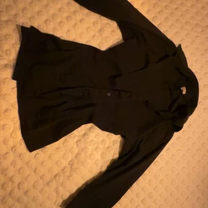 Svart skjorta med knappar - Snygg svart skjorta med långa ärmar och knappar framtill. Perfekt för en stilren look. Skjortan har en klassisk design som passar till många tillfällen. Original pris 549kr! Priset kan diskuteras. Storlek M men passar S