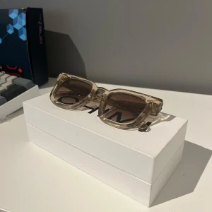 Transparenta solglasögon från CHIMI - ”Model 04” Snygga solglasögon från CHIMI med fyrkantig form och beige tonade linser. Perfekta för en stilren look. Kommer med allt orginalt