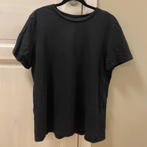 Svart t-shirt  - Säljer en klassisk svart t-shirt från Vero Moda i storlek L. T-shirten är kortärmad och lång, perfekt för en stilren look. Passar till alla tillfällen och är lätt att matcha med andra plagg.