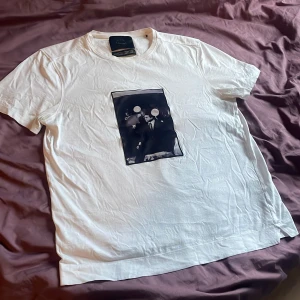 Vit t-shirt från Limitato - Säljer en Limitato T-shirt med ett snyggt svartvitt tryck av Muhammad Ali på framsidan. T-shirten har en klassisk passform och är kortärmad. Perfekt för dig som vill ha en stilren look med en ikonisk touch. Trycket är gjort av något material som är väldigt lent. Otroligt skön! Nypris: 1500kr Skriv vid funderingar 🔥