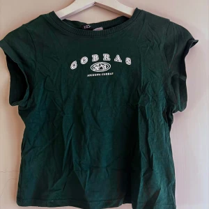 Grön t-shirt med tryck - Säljer en grön t-shirt med tryck från H&M.   Rensar ur min garderob just nu🌼 Kika och se om du ser något mer i min profil som du gillar så skickar jag med det till dig också!😊 Fler kläder kommer! 
