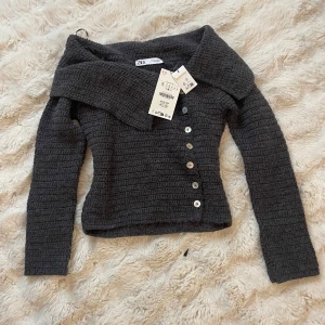 Grå stickad kofta från Zara - Säljer en snygg grå stickad kofta från Zara med knappar framtill. Koftan har en unik krage och långa ärmar, perfekt för kyligare dagar. Ett stilrent plagg som passar till många tillfällen. Helt ny dessutom💞💞