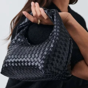Svart flätad handväska - Snygg svart handväska med flätat mönster. Perfekt för att ge en stilren touch till din outfit. Väskan har ett bekvämt handtag och är tillverkad i ett elegant material.