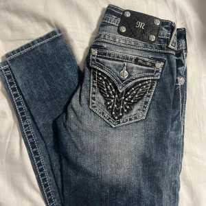 Blå jeans från Miss Me - Snygga blå jeans från Miss Me med dekorativa detaljer på bakfickorna. Jeansen har en cool slitning och kontrastsömmar som ger en unik look. Säljs då dom är alldeles för små på mig annars i fint skick🤩
