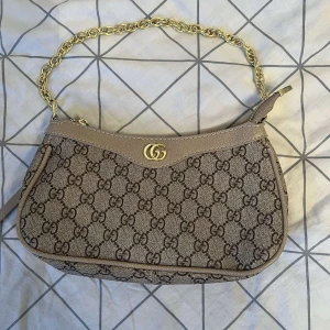 Beige och brun axelväska med kedja - Säljer min helt nya väska som jag inte längre använder, använd endast en gång. Perfekt för att ge din outfit en lyxig touch. Pris kan diskuteras vid snabb affär 