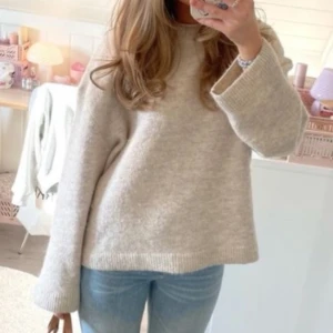 Beige stickad tröja - Mysig beige stickad tröja med långa ärmar och en avslappnad passform. Perfekt för kyligare dagar och enkel att matcha med olika outfits.