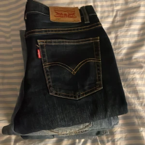 Jeans i olika tvättar - Säljer en samling av jeans i olika tvättar. Första paret är mörkblå Levis med klassisk design och kontrastsömmar. Andra paret är ljusblåa Replay jeans med en vintage look. Perfekta för en avslappnad stil.