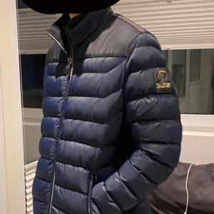 Blå pufferjacka från Parajumpers - Säljer en snygg blå pufferjacka från Parajumpers med quiltad design och dragkedja framtill. Jackan har en broderad logga på ärmen och svarta axelpartier. Perfekt för kyliga dagar! Aldrig använd! Denna kostar 490kr, men vid köp tillsammans med den andra jackan i min annons får man båda för 790kr!