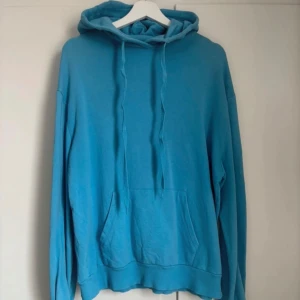 Blå hoodie - Säljer en blå hoodie med luva och dragsko. Tröjan har en ficka framtill. Tröjan har även lite slitage, se sista bild.