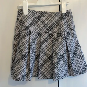 Minikjol - Snygg grå rutig kjol från H&M i en klassisk kort modell. Kjolen har ett stilrent rutmönster och är perfekt för en trendig look. Passar utmärkt till både vardag och speciella tillfällen.