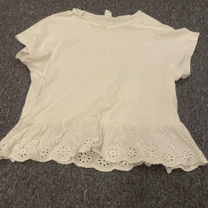 Vit topp med spetsdetaljer från Shein - Säljer en söt vit topp från Shein med korta ärmar och fina spetsdetaljer längst ner. Perfekt för en somrig look. Toppen är i en mjuk och bekväm bomullsmix.