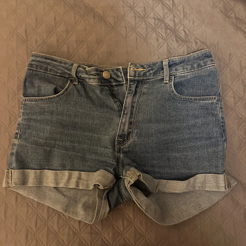 Säljer ett par klassiska blå jeansshorts med normal midja. De har en snygg uppvikt kant och femficksdesign. Perfekta för en sommarkväll 💗. Shortsit.