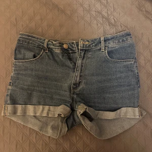 Blå jeansshorts - Säljer ett par klassiska blå jeansshorts med normal midja. De har en snygg uppvikt kant och femficksdesign. Perfekta för en sommarkväll 💗