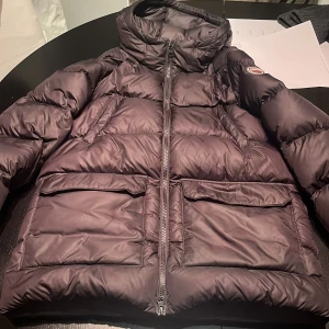 Svart dunjacka från Colmar - Säljer en snygg svart dunjacka från Colmar. Jackan har en dragkedja framtill och en hög krage för extra värme. Den är perfekt för kalla dagar och har en stilren design med Colmars logga på bröstet.