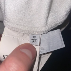 Vit huvtröja från Stone Island  - Säljer en stilren vit huvtröja från Stone Island . Tröjan har en dragkedja framtill och en ikonisk logga på ärmen. Perfekt för en avslappnad look. Skulle säga att den passar runt 160