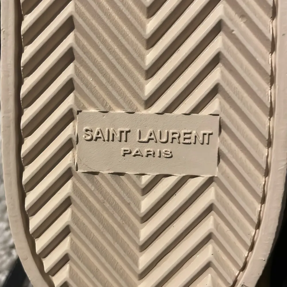 Snygga svarta sneakers från Saint Laurent med vit sula och märkets logotyp i vitt på sidan. Skorna har snörning och är tillverkade i skinn, vilket ger en lyxig känsla. Perfekta för en stilren look. Kvitto finns ! Om ni är intresserade . Kengät.
