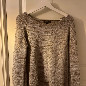 Beige stickad tröja från Alice Bizous - Säljer en stilren beige stickad tröja från Alice Bizous. Tröjan har långa ärmar och ett litet skimmrigt garn.